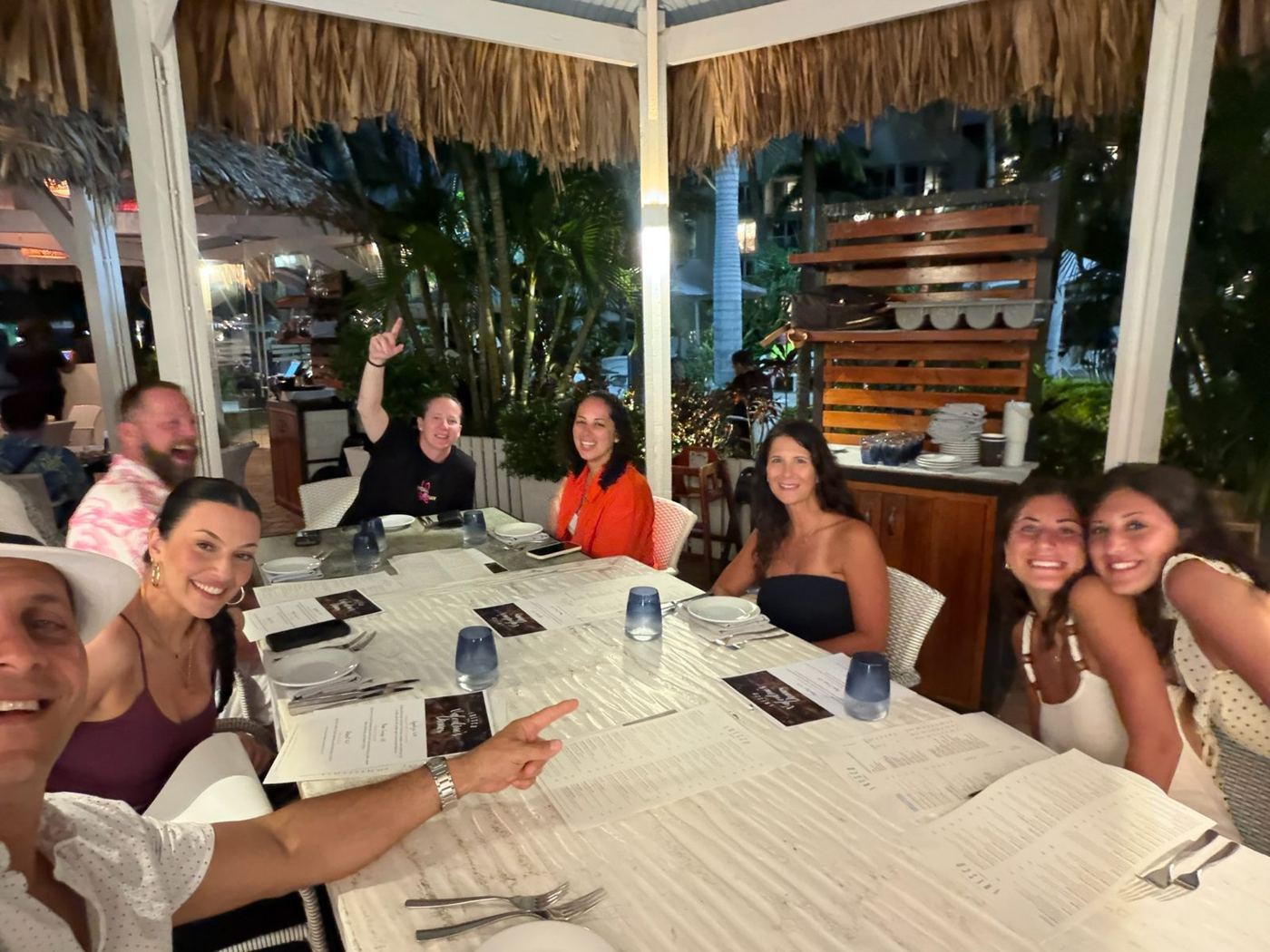 Friends at a dinner table under a palapa