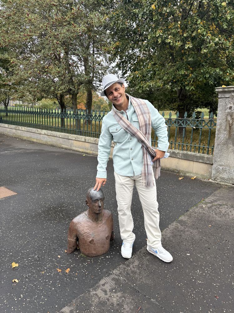 Rob patting the head of a bronze statue on a sidewalk