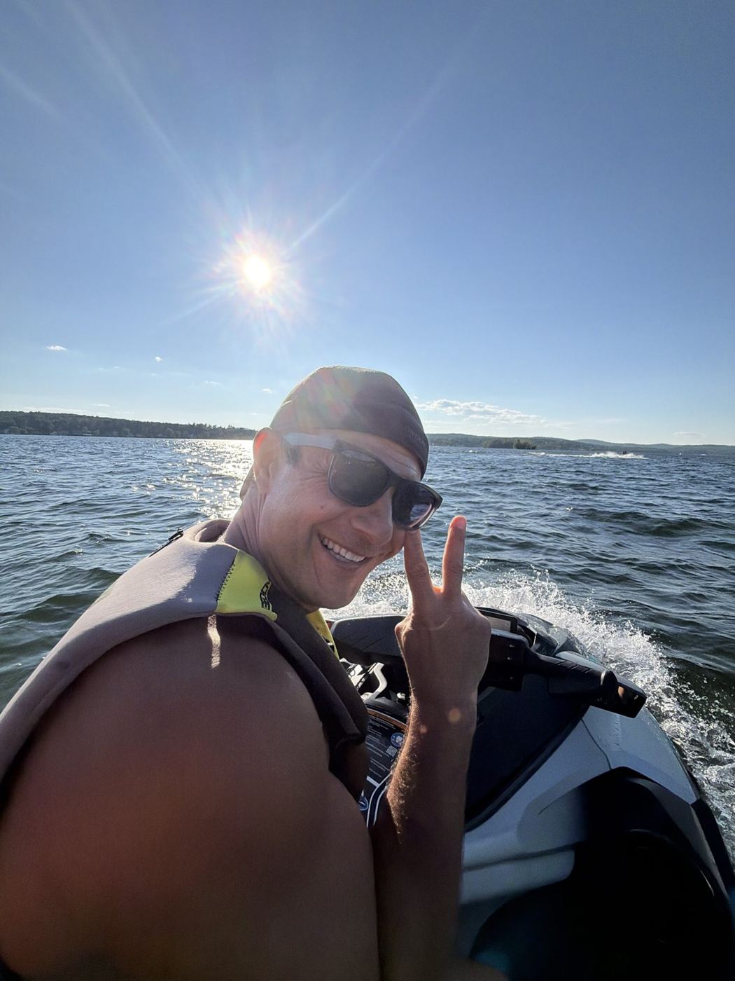 Rob on a jet ski at sunset flashing a peace sign